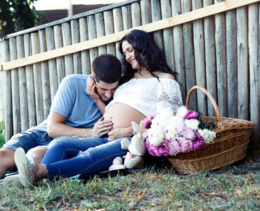 man leans woman s pregnant belly while she sits wooden fence man leans woman s pregnant belly while she sits wooden fence