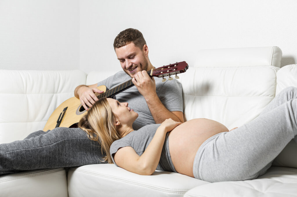 pregnant woman listening her husband playing guitar pregnant woman listening her husband playing guitar