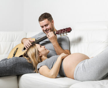 pregnant woman listening her husband playing guitar pregnant woman listening her husband playing guitar