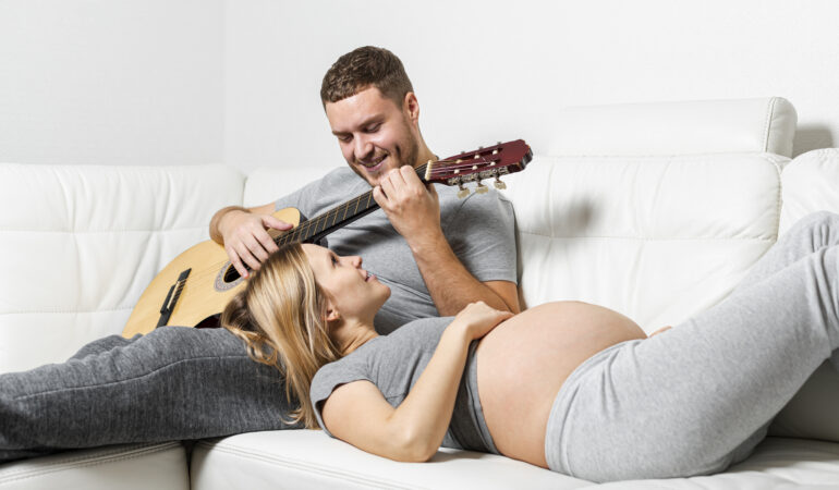 pregnant woman listening her husband playing guitar pregnant woman listening her husband playing guitar