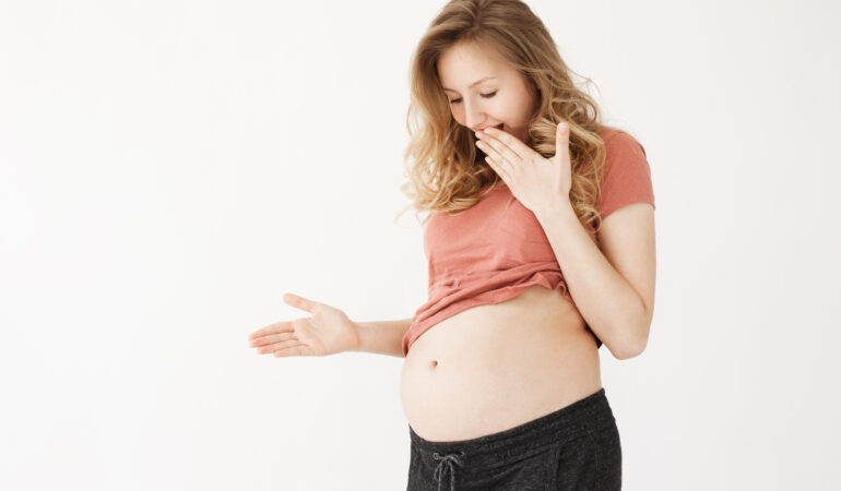 young beautiful good looking blonde pregnant woman with long hair crazy clothes closing mouth with hand looking her belly when baby pushes stomach with leg young beautiful good looking blonde pregnant woman with long hair crazy clothes closing mouth with hand looking her belly when baby pushes stomach with leg